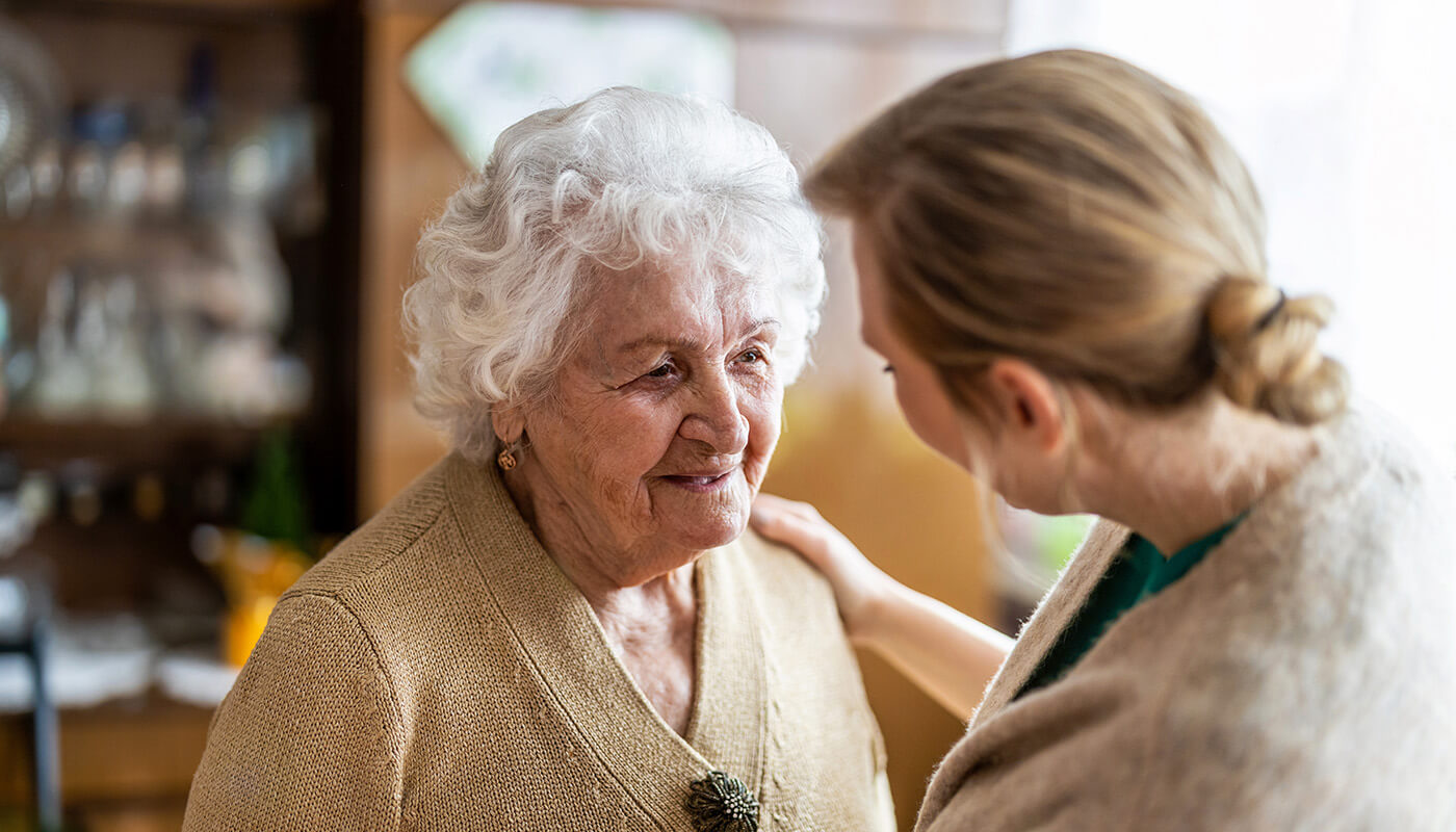 Senior woman is embraced by younger female
